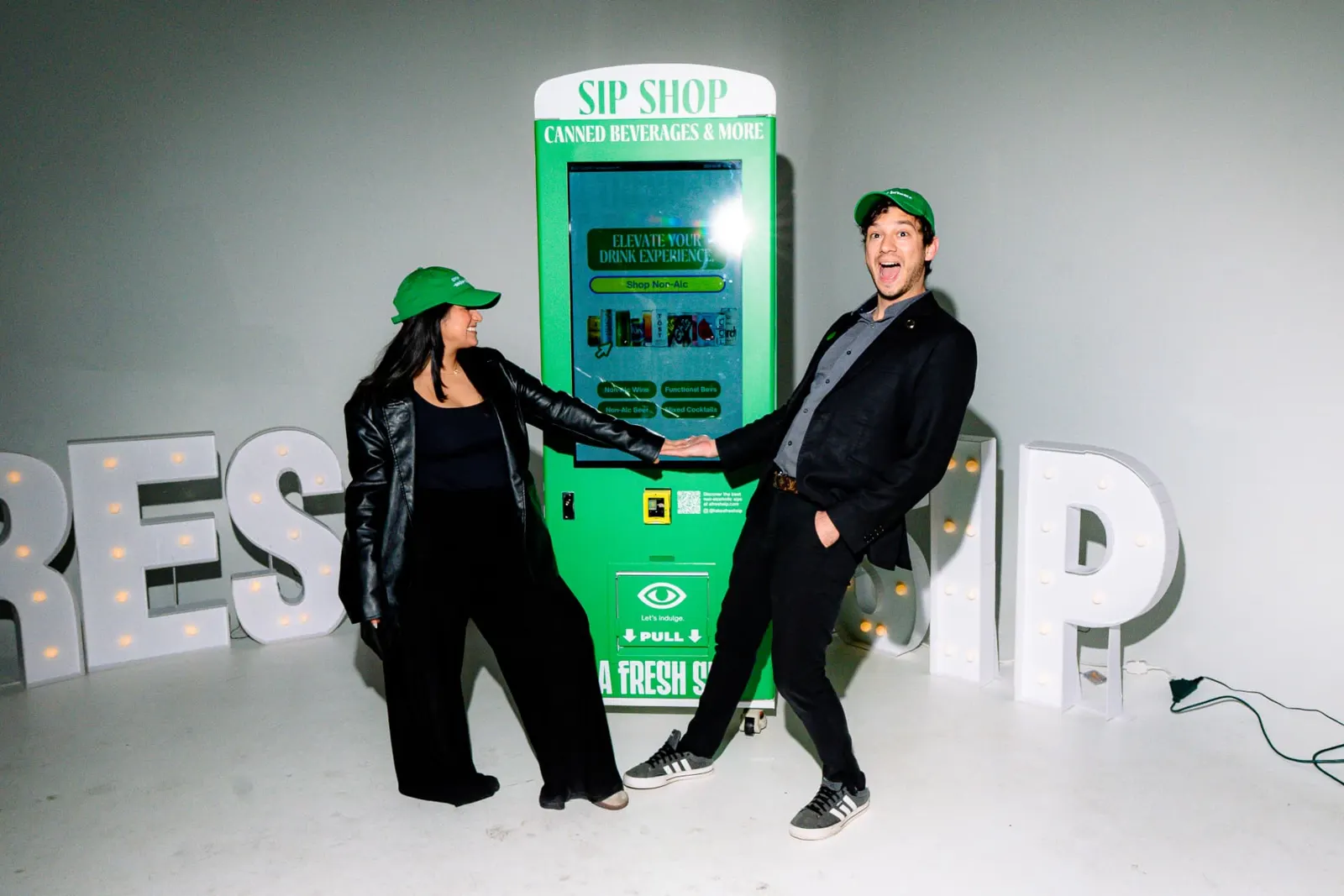 Guests in A Fresh Sip caps using the Sip Shop vending machine touchscreen